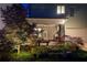 The backyard at night is adorned with ambient lighting and beautiful landscaping creating a captivating outdoor space at 164 Inwood Walk, Woodstock, GA 30188