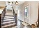 Inviting entryway featuring hardwood floors, staircase with dark wood, and natural light from the front door at 164 Inwood Walk, Woodstock, GA 30188