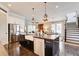 Open kitchen with stainless steel appliances, farmhouse sink, dark island, and seamless flow into the living area at 164 Inwood Walk, Woodstock, GA 30188