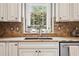 Close-up of the kitchen sink featuring granite countertops, a tiled backsplash, and garden view at 1800 Hunters Moon Dr, Alpharetta, GA 30005