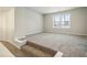 A carpeted living room featuring neutral walls, a window, and access to other rooms at 616 Rodeo Dr, Auburn, GA 30011