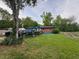 Expansive side view of home exterior, showing lawn, trees, and a large dumpster, set against a lush green backdrop at 1934 Apache Se Trl, Atlanta, GA 30316