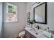 Charming powder room features a modern vanity, framed mirror, and a window with a wooded view at 235 W Marietta St, Canton, GA 30114
