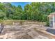 View of the backyard features a split rail fence, tree line, and a concrete patio at 3706 Bouldercrest Rd, Ellenwood, GA 30294