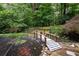 Backyard view of a pond with a wooden bridge surrounded by mature trees at 735 Wood Valley Trce, Roswell, GA 30076