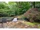Backyard view of a pond with a wooden bridge surrounded by mature trees at 735 Wood Valley Trce, Roswell, GA 30076