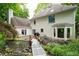 Charming backyard with lush greenery, a serene pond, and a quaint bridge leading to the home at 735 Wood Valley Trce, Roswell, GA 30076