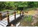 Backyard view of a pond with a wooden bridge surrounded by mature trees at 735 Wood Valley Trce, Roswell, GA 30076