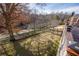 Backyard featuring a manicured lawn, mature trees, black metal fence, and partial view of an estate home at 2760 Sugarloaf Club Dr, Duluth, GA 30097