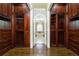 Walk-in closet featuring custom cabinetry, glass-front display cases, and hardwood floors at 2760 Sugarloaf Club Dr, Duluth, GA 30097