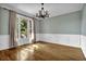 Dining room featuring hardwood floors, wainscoting, modern light fixture, and a large window at 3875 Sweetwater Dr, Cumming, GA 30041