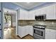 Modern kitchen featuring stainless steel appliances, granite counters, and white cabinets with tiled backsplash at 3875 Sweetwater Dr, Cumming, GA 30041