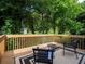 This home's wood deck has furniture and a railing looking out over a large lawn and wooded area at 803 Plantation Ridge Overlook, Woodstock, GA 30188