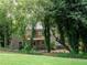 Home's back exterior features a walk-out basement and large deck, surrounded by mature shade trees at 803 Plantation Ridge Overlook, Woodstock, GA 30188