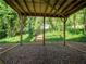 View from covered patio with rock flooring, stairs leading into the backyard, and many surrounding mature trees at 803 Plantation Ridge Overlook, Woodstock, GA 30188