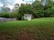 Large backyard with a storage shed, surrounded by a wood fence and mature trees at 803 Plantation Ridge Overlook, Woodstock, GA 30188