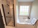 Relaxing bathtub with modern fixtures, a shower with glass doors, and large window at 803 Plantation Ridge Overlook, Woodstock, GA 30188