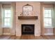 Stone fireplace with a wood mantel and mirror between two windows with natural light at 803 Plantation Ridge Overlook, Woodstock, GA 30188