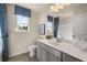 Bright bathroom featuring gray cabinetry, white countertops, and a framed mirror reflecting the shower and window at 13574 Se Whitman Ln, Covington, GA 30014