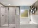 Modern bathroom with a tiled shower, bathtub, and a window with natural light at 13574 Se Whitman Ln, Covington, GA 30014