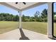 A covered patio looks out onto a wide lawn area and wooded area in the distance at 13574 Se Whitman Ln, Covington, GA 30014