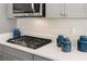 Close up of a gas cooktop installed in a white countertop with matching blue decor at 13574 Se Whitman Ln, Covington, GA 30014