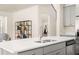 Bright kitchen island with white countertop, stainless steel sink, and view to the staircase at 13574 Se Whitman Ln, Covington, GA 30014
