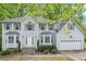 Classic two-story home with large windows, a manicured lawn, and an attached two-car garage at 6230 Lillie Ln, Cumming, GA 30040