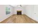 Living room featuring wood floors, a cozy fireplace, and natural light from a large window at 6230 Lillie Ln, Cumming, GA 30040