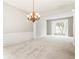 Bright living room with elegant chandelier, carpet, and bay window provides ample space at 144 Nocatee Trl, Woodstock, GA 30188