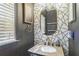 Stylish half-bathroom featuring geometric wallpaper, granite countertops, and modern gold fixtures at 2260 Cobble Creek Ln, Grayson, GA 30017