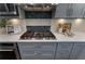 Close-up of kitchen features: gas range with stainless hood, decorative backsplash, & white quartz countertops at 5828 Paliser Trce, Sugar Hill, GA 30518