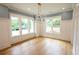 Airy dining room with wainscoting, large windows, modern lighting, and wood flooring at 219 Poplar Nw St, Lilburn, GA 30047