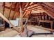 View of unfinished attic with exposed wooden beams, plywood floor, and stored furniture at 3030 Spalding Dr, Sandy Springs, GA 30350