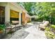 An outdoor patio with a flagstone floor is furnished with chairs and tables under the shade of lush trees at 3030 Spalding Dr, Sandy Springs, GA 30350