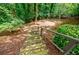 Backyard with wooden stairs leading to a play area surrounded by lush greenery and mature trees at 3030 Spalding Dr, Sandy Springs, GA 30350