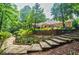 Picturesque backyard featuring stone steps, lush landscaping, and the home's exterior in a serene outdoor setting at 3030 Spalding Dr, Sandy Springs, GA 30350