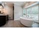Spa bathroom with soaking tub, dark wood vanities, large windows, and hardwood style flooring at 3030 Spalding Dr, Sandy Springs, GA 30350