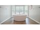 Bright bathroom featuring a freestanding tub under a large window with wooden-look tile floors at 3030 Spalding Dr, Sandy Springs, GA 30350