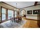 Traditional dining room with wooden table, chairs, wood floors, large windows, and arched doorway at 3030 Spalding Dr, Sandy Springs, GA 30350