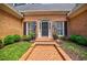 Inviting front entrance with a brick pathway, dark door, black shutters, and potted flowers at 3030 Spalding Dr, Sandy Springs, GA 30350