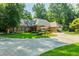 Charming brick home with a circular driveway and well-manicured lawn, shaded by mature trees at 3030 Spalding Dr, Sandy Springs, GA 30350