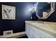 Elegant powder room with dark blue walls, gold accents, framed art, and a vintage-style mirror at 3030 Spalding Dr, Sandy Springs, GA 30350