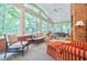 Bright sunroom with exposed brick wall, ceiling fan, and many windows offering a view of the trees at 3030 Spalding Dr, Sandy Springs, GA 30350