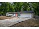 Low angle of a bright white home with dark shutters, orange door, and a large driveway with an attached two-car garage at 5640 Redan Cir, Stone Mountain, GA 30088