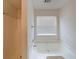 A clean bathroom featuring a large white tub with tiled walls and a window with blinds at 2374 Brandenberry Ct, Decatur, GA 30034
