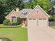 Charming brick home featuring a manicured lawn and an attached two-car garage at 7615 Abbey Glen Dr, Cumming, GA 30028