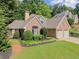 Traditional brick home with a well-manicured lawn, mature trees, and an attached two-car garage at 7615 Abbey Glen Dr, Cumming, GA 30028