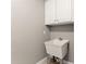A simple laundry sink features tile floors and white cabinets at 7615 Abbey Glen Dr, Cumming, GA 30028