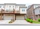 Rear exterior view of a townhouse with a wooden deck overlooking the driveway and garage at 3195 Bartee Walk, Suwanee, GA 30024